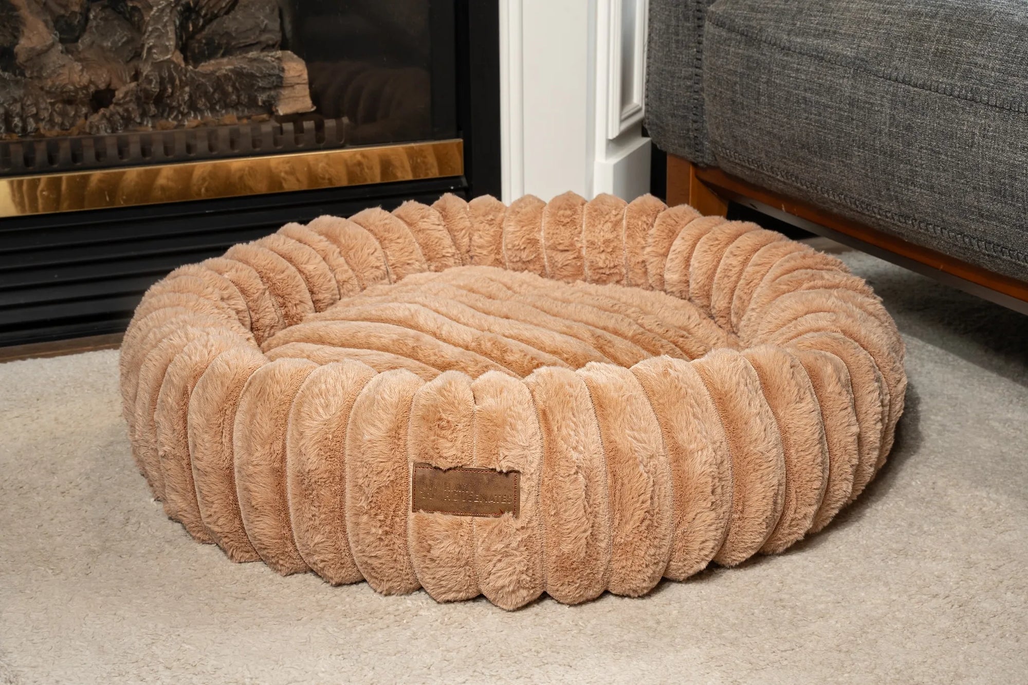 A sienna corduroy bed by the fireplace in a real living room