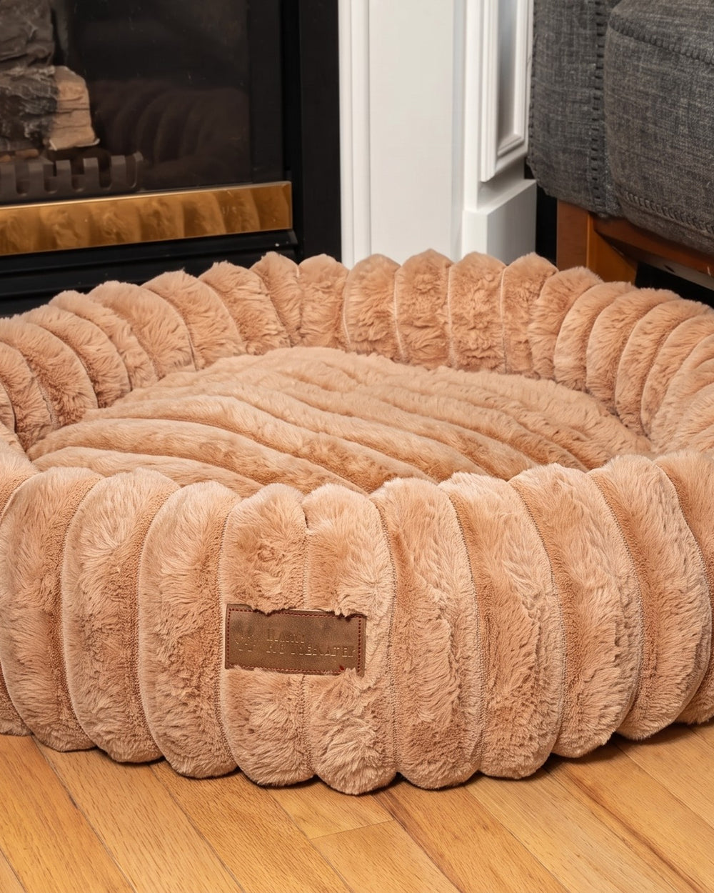 Sand corduroy dog bed by the fireplace on a wooden floor in a real living room